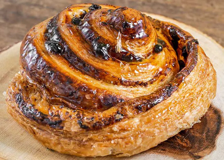 mage of a tray of freshly baked classic escargot pastry on a wood board.