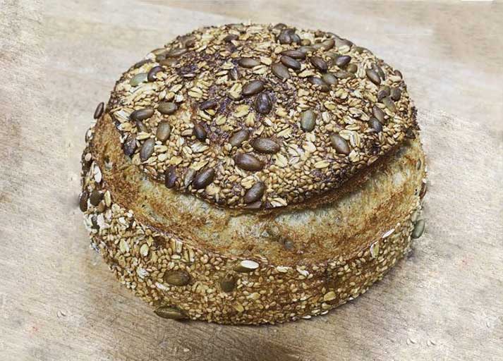 Image of a multigrain sourdough loaf, made with a variety of grains including wheat, oats, barley, and rye, and slow-fermented for a unique and complex flavor. The loaf has a golden-brown crust and a dense, hearty texture.