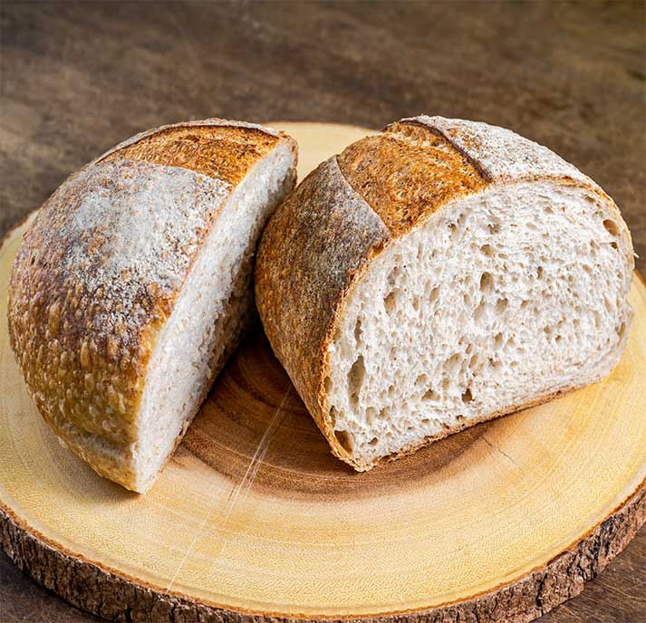 Whole wheat sourdough loaf with a unique, tangy flavor made with whole wheat flour and a sourdough starter, packed with nutrients on a wood board.